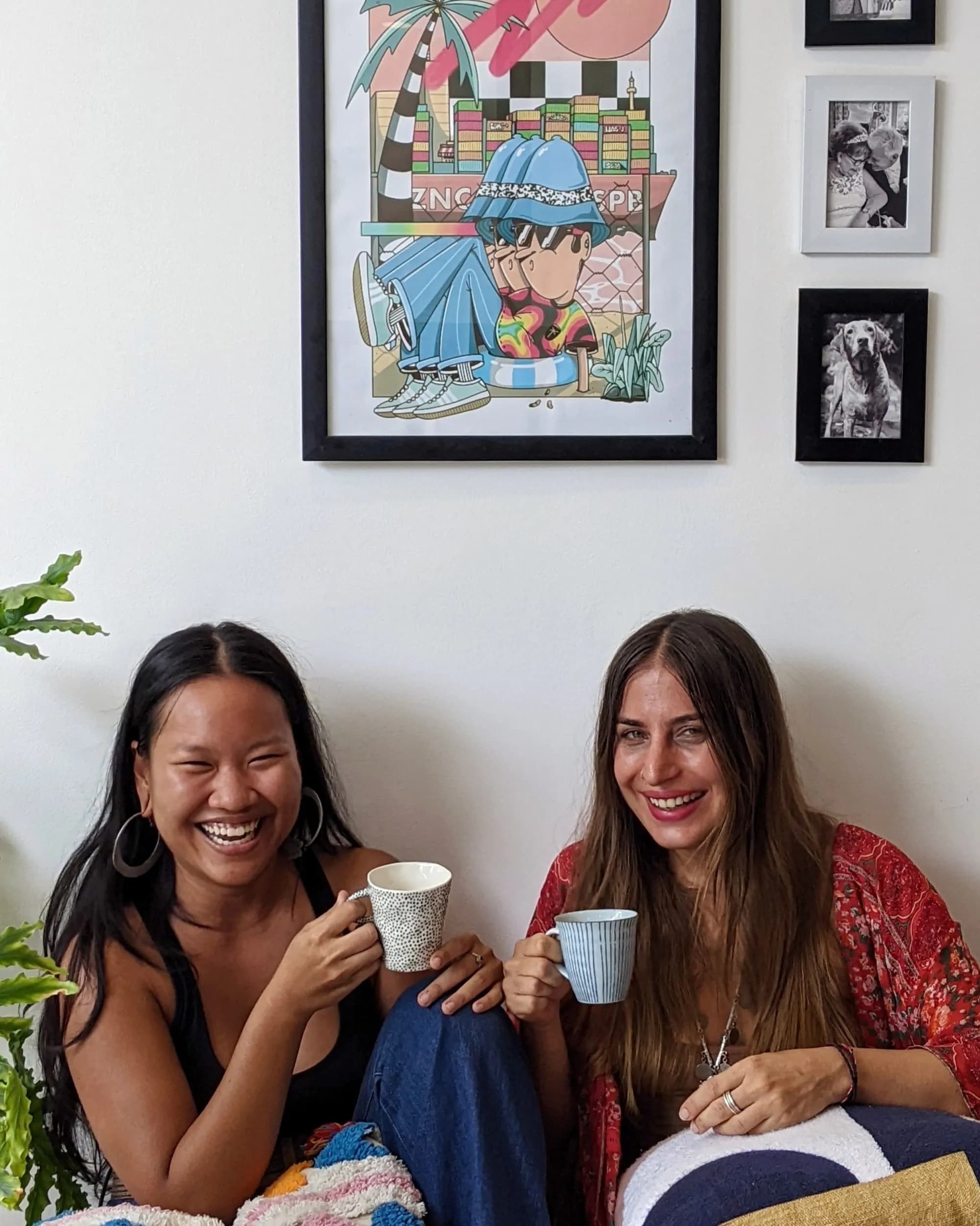 the two founders of Baked & Friends sitting together, laughing over coffee, with framed art behind them